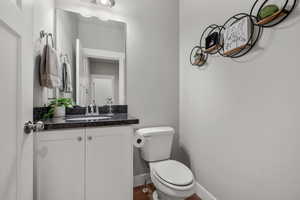 Half bath featuring toilet, baseboards, and vanity