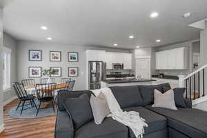 Living room with light wood-style flooring, stairs, baseboards, and recessed lighting