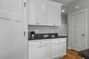 Kitchen with white cabinetry, light wood finished floors, dark stone counters, and recessed lighting