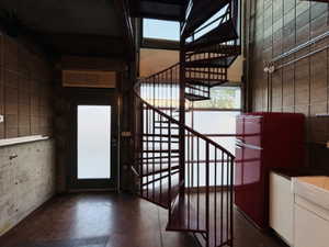 Stairs featuring a wealth of natural light, finished concrete flooring, and a towering ceiling