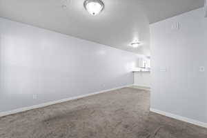 Carpeted spare room featuring baseboards and a textured ceiling