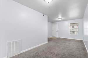 Unfurnished room with carpet, visible vents, and baseboards