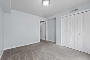 Unfurnished bedroom with a closet, visible vents, baseboards, and carpet floors
