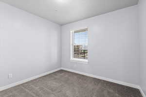 Spare room with dark colored carpet and baseboards