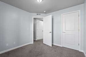 Unfurnished bedroom with carpet flooring, visible vents, and baseboards