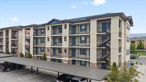 View of property featuring covered and uncovered parking