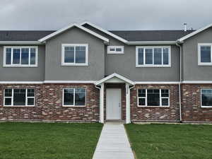 View of front of house with stucco siding, brick siding, and a front lawn