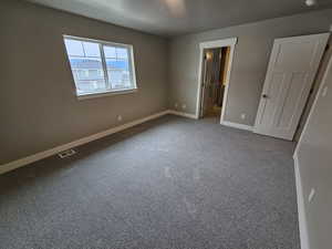 Unfurnished bedroom with carpet floors, a textured ceiling, visible vents, baseboards, and ensuite bathroom