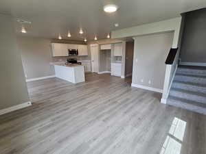 Kitchen featuring a peninsula, stainless steel appliances, visible vents, open floor plan, and baseboards