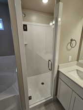 Full bath with vanity, a textured ceiling, a stall shower, tile patterned flooring, and a bath