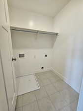 Clothes washing area featuring laundry area, light tile patterned floors, electric dryer hookup, baseboards, and hookup for a washing machine