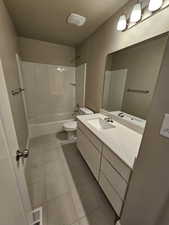 Bathroom with toilet,  shower combination, tile patterned floors, a textured ceiling, and vanity