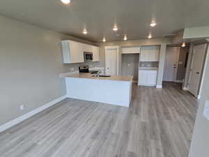 Kitchen with stainless steel appliances, baseboards, a sink, a peninsula, and light countertops