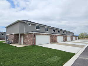 View of property featuring an attached garage, stucco siding, concrete driveway, central AC unit, and a front yard