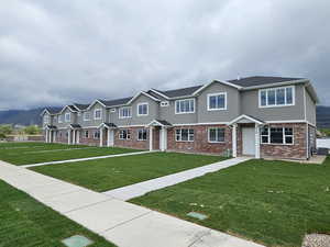 Multi unit property featuring a residential view, stucco siding, brick siding, and a front lawn