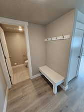 Mudroom with a textured ceiling, wood finished floors, and baseboards