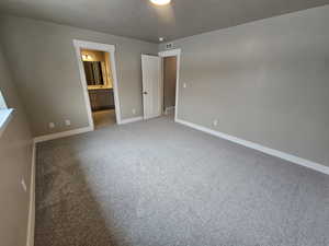 Unfurnished bedroom featuring a textured ceiling, baseboards, visible vents, connected bathroom, and carpet floors