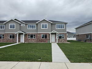 View of front of property with central AC, stucco siding, fence, a front lawn, and brick siding