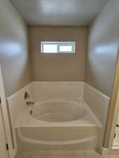 Full bath with a textured ceiling, a garden tub, and tile patterned floors
