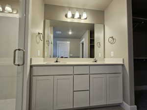 Bathroom featuring a sink, double vanity, and a shower stall