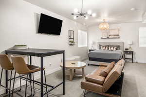 Bedroom with baseboards, a notable chandelier, and carpet
