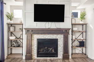 Room details with a tiled fireplace, baseboards, and wood finished floors