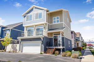 View of front of home with a garage, fence, a balcony, and driveway
