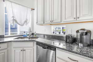 Kitchen featuring a sink, white cabinets, stainless steel dishwasher, and a healthy amount of sunlight