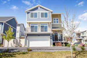 View of front facade featuring fence, an attached garage, driveway, and a balcony