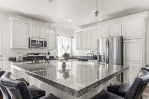 Kitchen with white cabinets, stainless steel appliances, and a breakfast bar