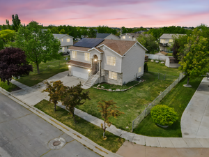View of front facade with an attached garage, roof mounted solar panels, a lawn, a fenced backyard, and driveway