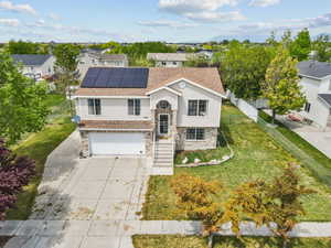 Raised ranch with a residential view, a garage, solar panels, a front yard, and driveway