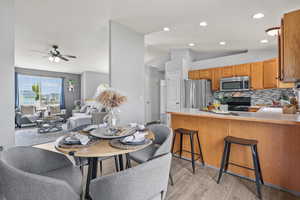Dining space with light wood finished floors, lofted ceiling, a ceiling fan, and recessed lighting