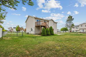 Rear view of house featuring a lawn, a wooden deck, a fenced backyard, and a gate