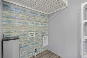 Laundry room featuring wood walls, wood finished floors, laundry area, electric dryer hookup, and hookup for a washing machine