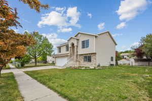 Split level home with concrete driveway, a garage, a front lawn, and fence