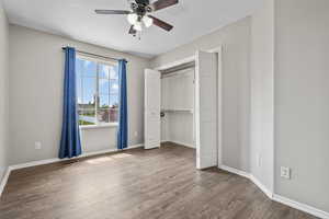 Unfurnished bedroom featuring a closet, visible vents, wood finished floors, and baseboards