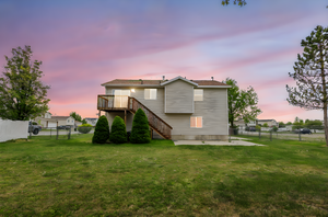 Rear view of property featuring a yard, stairway, and a fenced backyard