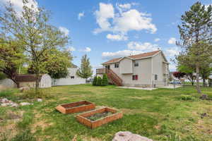 View of yard featuring an outdoor structure, a shed, a garden, stairway, and a fenced backyard