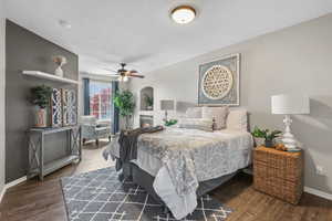 Bedroom with a textured ceiling, baseboards, ceiling fan, wood finished floors, and arched walkways