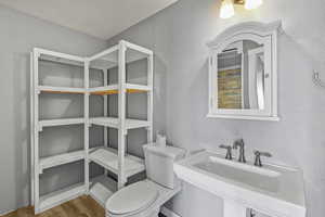 Bathroom with toilet, wood finished floors, and a sink
