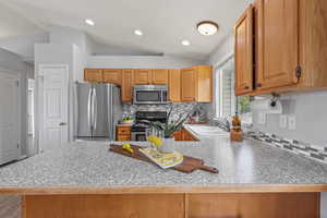 Kitchen with stainless steel appliances, a peninsula, a sink, and vaulted ceiling