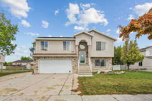 Split foyer home with roof mounted solar panels, a garage, a front lawn, concrete driveway, and brick siding