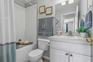 Full bathroom with toilet, vanity, and shower / bathtub combination with curtain