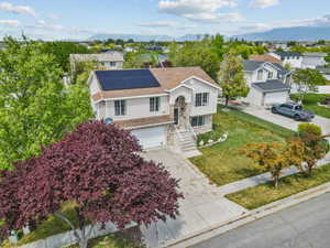 Raised ranch with roof mounted solar panels, a garage, a residential view, and driveway