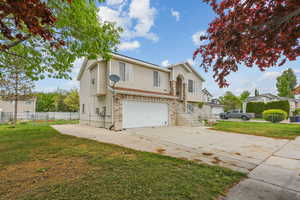 Traditional-style house with concrete driveway, an attached garage, fence, and a front yard