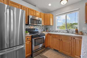 Kitchen featuring lofted ceiling, stainless steel appliances, dark wood-style flooring, light countertops, and tasteful backsplash