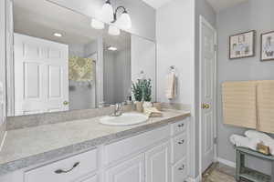 Bathroom featuring a shower with shower curtain, baseboards, and vanity