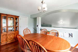 Dining area with ornate columns, a chandelier, and dark wood-style floors