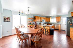 Dining area with dark wood-type flooring, a healthy amount of sunlight, and a notable chandelier